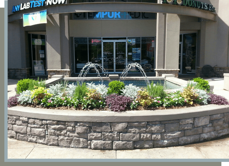 A fountain in the middle of a flower bed.