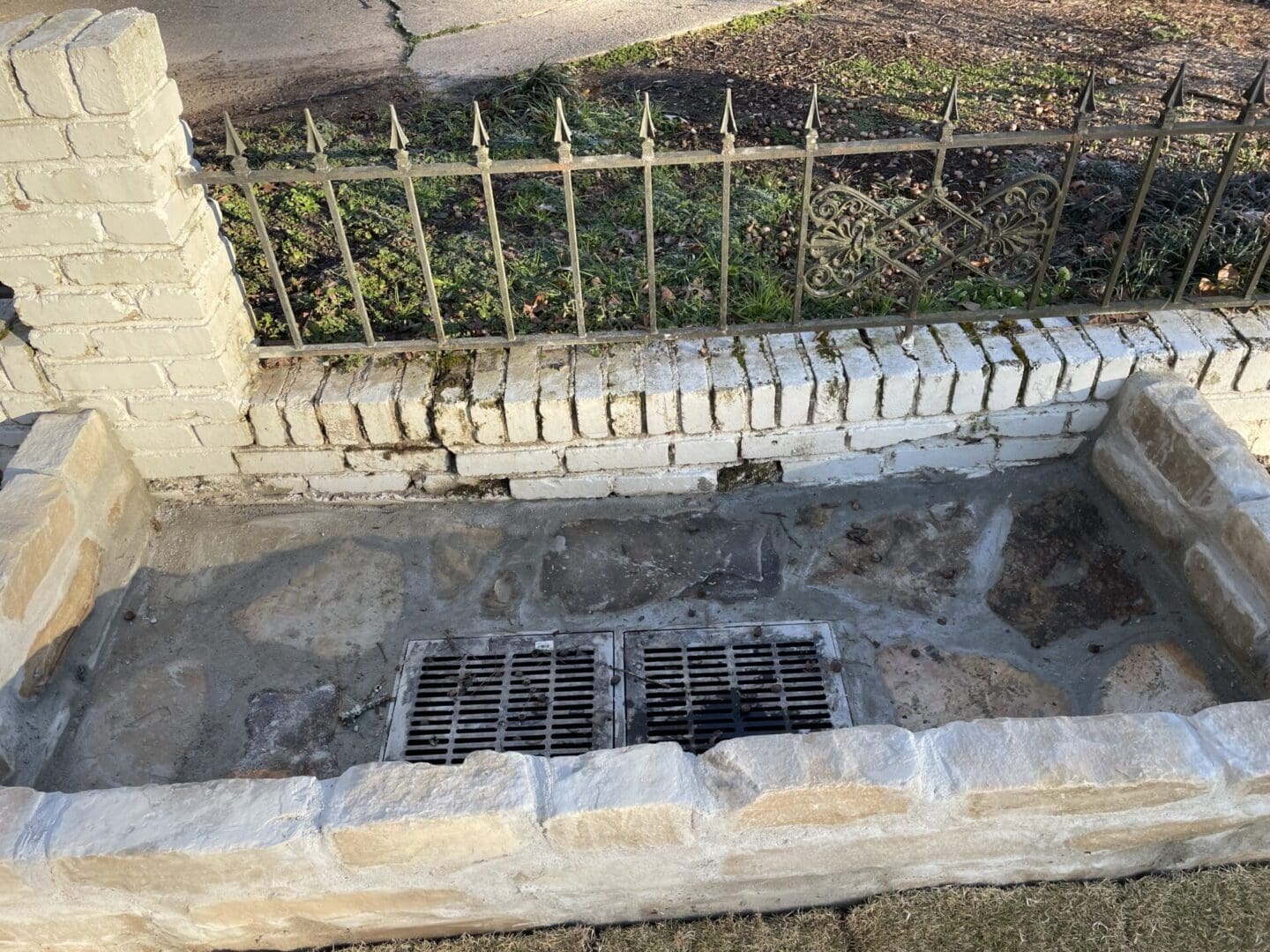 A brick walkway with a metal grate and stone steps.