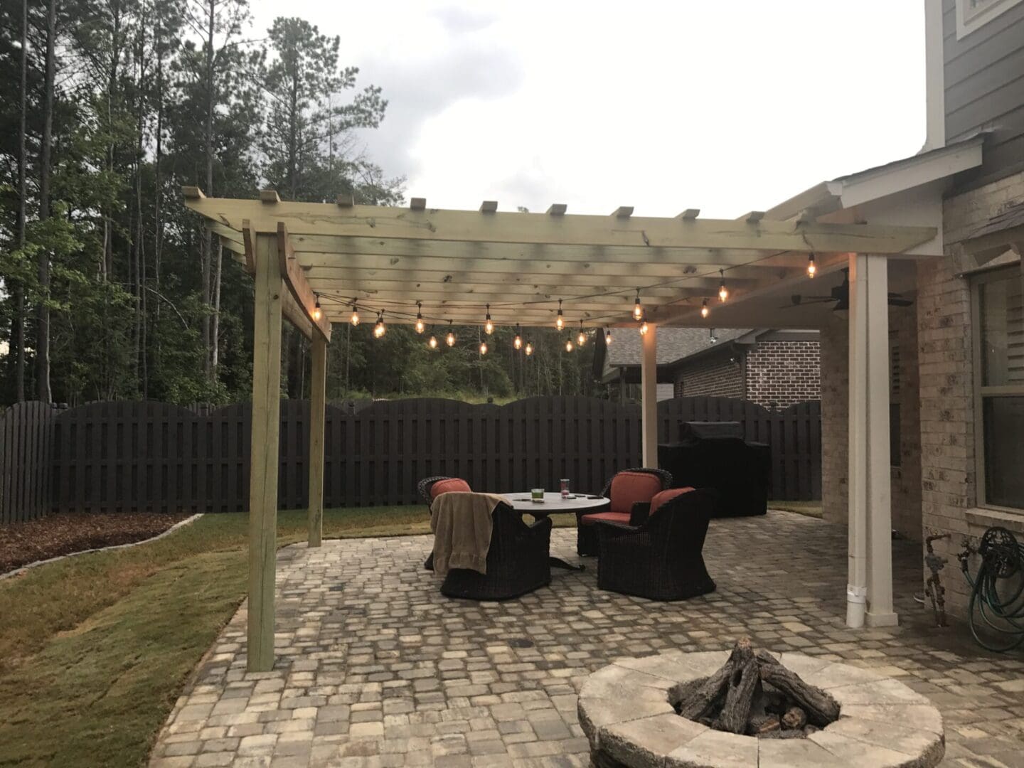 A patio with a fire pit and lights hanging from the roof.