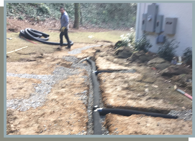 A man is walking on the ground near pipes.