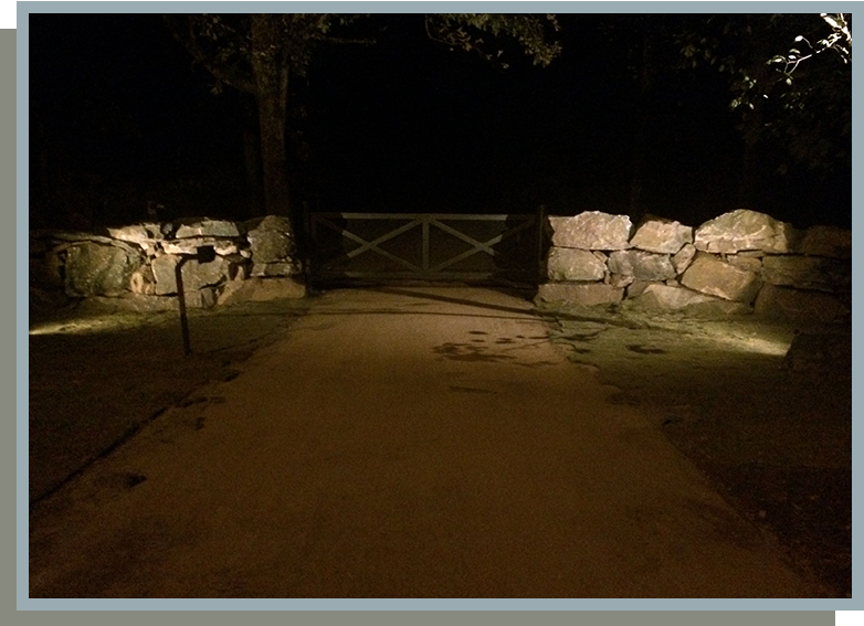 A dark picture of a driveway with stone walls.