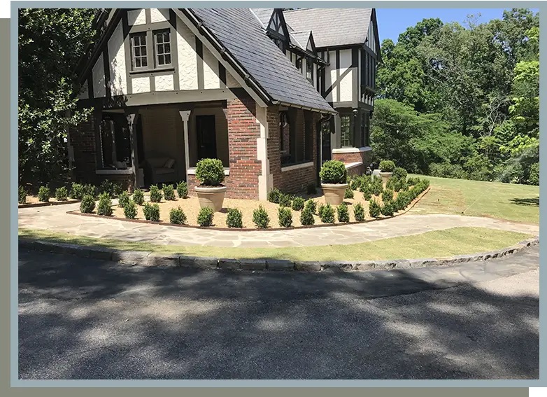 A house with a driveway and bushes in the front yard.